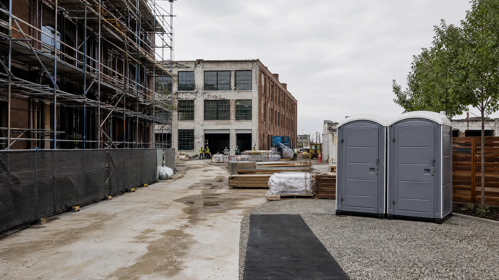Portable restroom area beside an unoccupied Orlando-area construction site with a compacted access path.